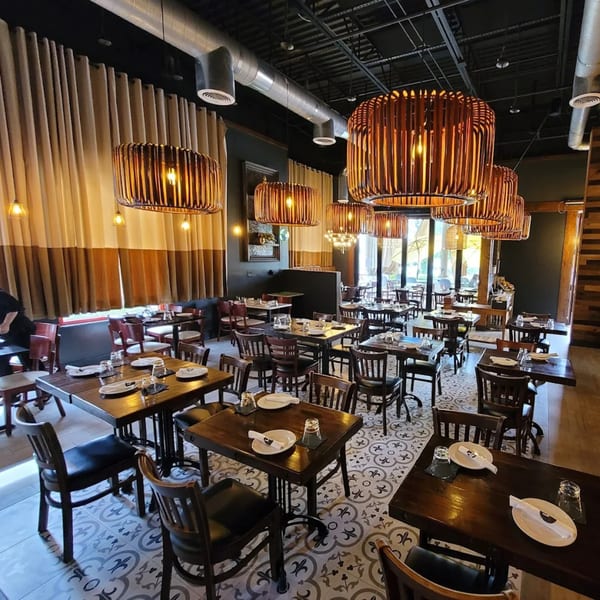 Interior of The Sea restaurant with dark wooden tables, chairs, patterned floor, and unique hanging lights.