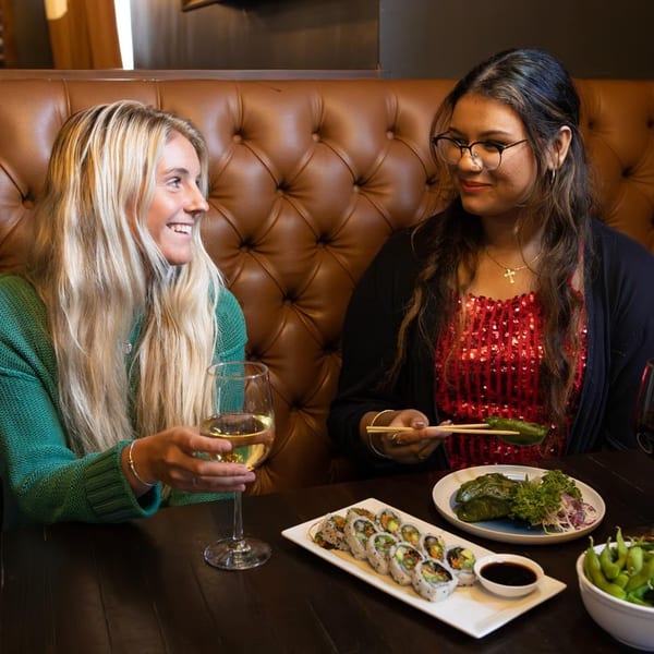 Two women enjoying sushi and drinks at The Sea South East Asian Kitchen and Sushi.