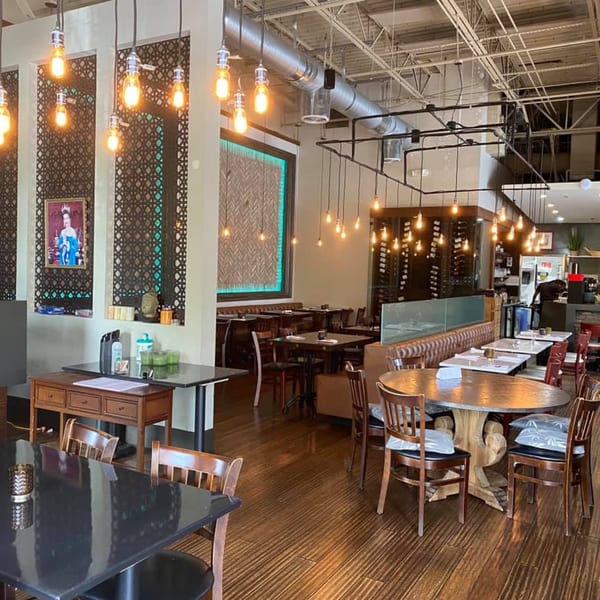 Interior of The Sea South East Asian Kitchen and Sushi, featuring dining tables, chairs, and decorative lighting.