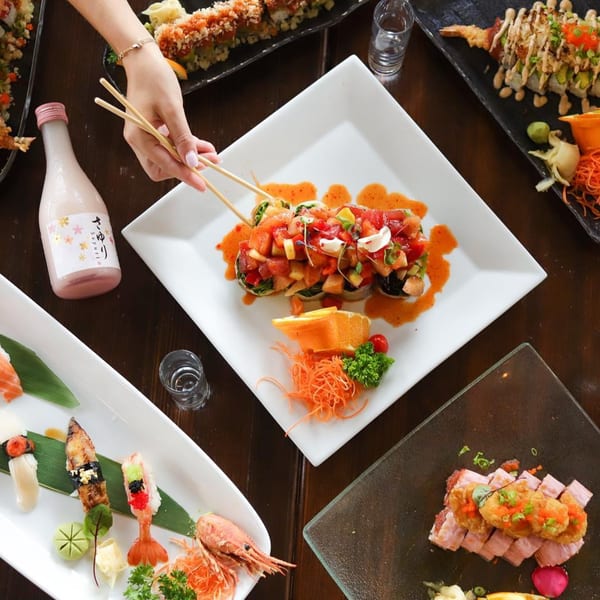 Overhead view of a table laden with various sushi rolls, sashimi, and a bottle of sake.